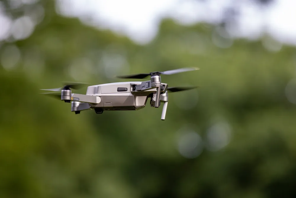 DJI-drone in vlucht tegen een achtergrond van bomen
