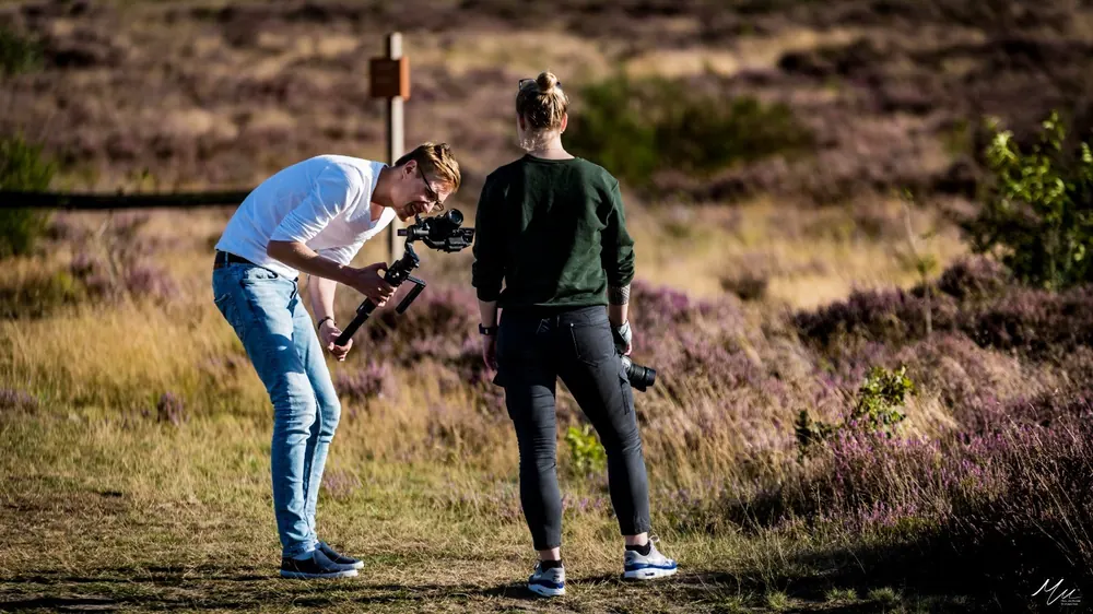 Twee videografen filmen samen met gimbal in een heidelandschap